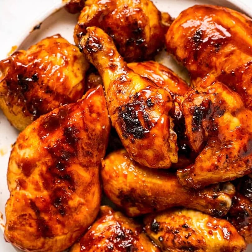 Close-up of Big Orange BBQ's glazed chicken pieces, including drumsticks and thighs, covered in rich BBQ sauce.