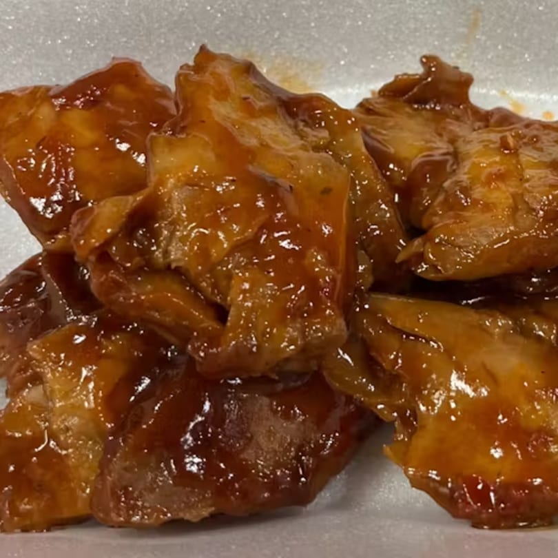 Close-up of Big Orange BBQ's chicken wings coated in a glistening, sticky brown sauce.