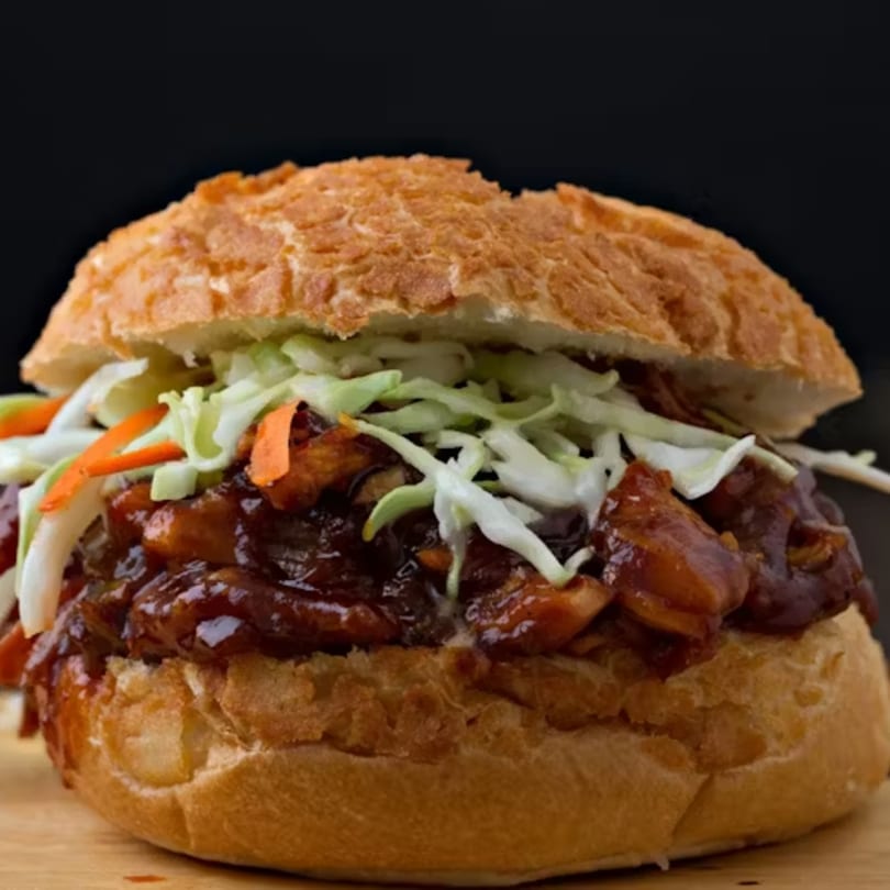 Close-up of a Big Orange BBQ pulled pork sandwich with coleslaw on a bun.